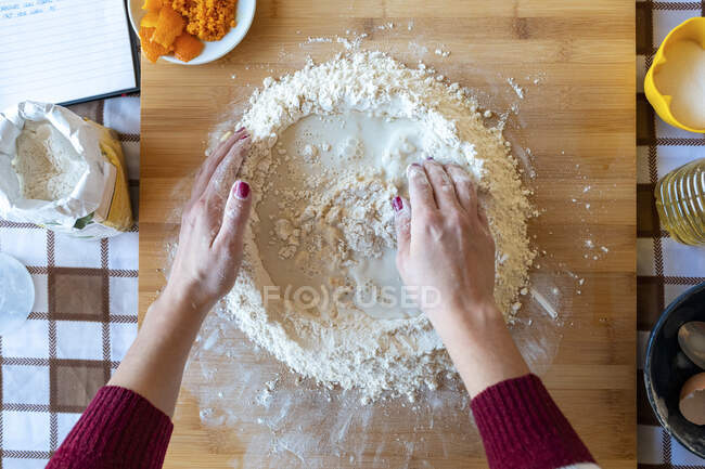 Mulher misturando leite e farinha na tábua de corte na cozinha — Fotografia de Stock