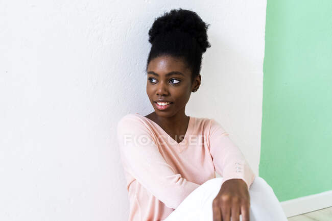 Giovane donna guardando lontano mentre seduto contro parete multicolore — Foto stock