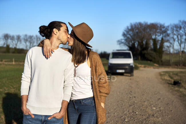 Coppia eterosessuale baciare mentre in piedi contro il cielo blu durante il tramonto — Foto stock