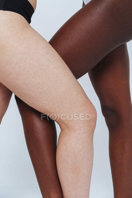 Donne in piedi con le gambe incrociate al ginocchio in studio — Foto stock