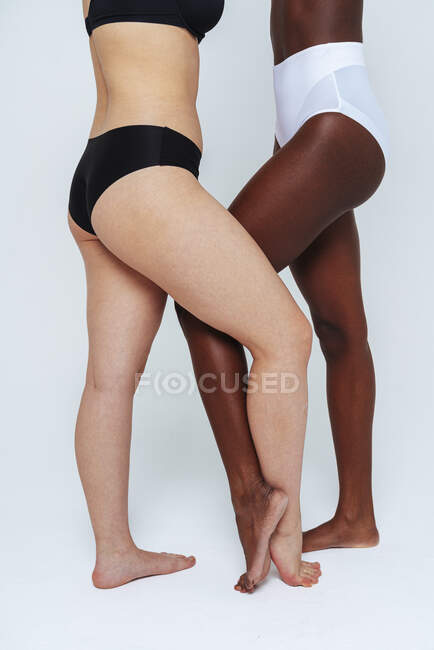 Junge Frauen in Dessous stehen mit am Knöchel gekreuzten Beinen im Studio — Stockfoto