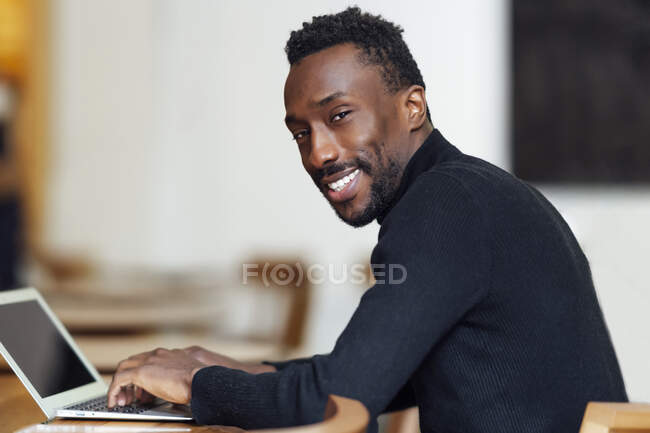 Geschäftsmann mit Laptop lächelt im Café — Stockfoto