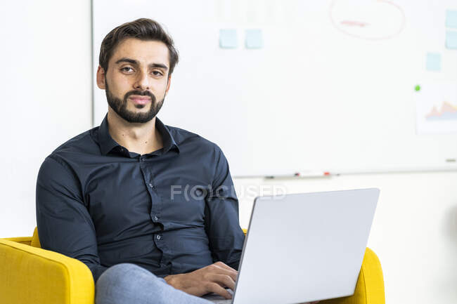 Молодий бізнесмен з ноутбуком під час роботи на стільці. — стокове фото