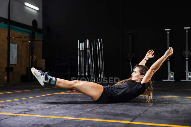 Giovane donna con le braccia alzate che esercita sul pavimento nel centro benessere — Foto stock