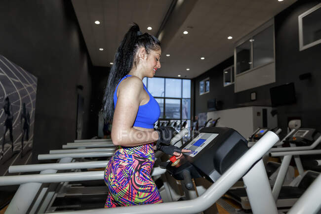 У спортзалі на біговій доріжці біжить доросла жінка. — стокове фото