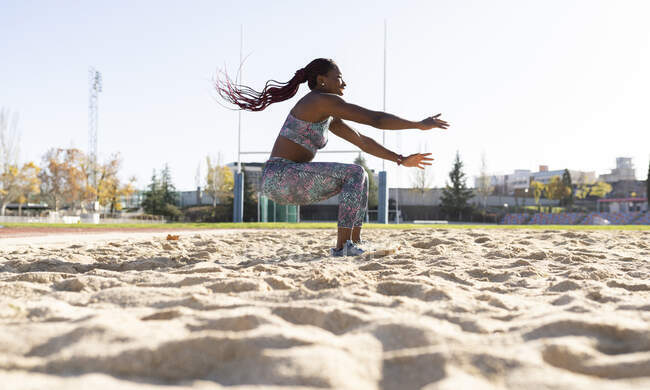 Женщина-спортсмен балансирует на песке против ясного неба в солнечный день — стоковое фото