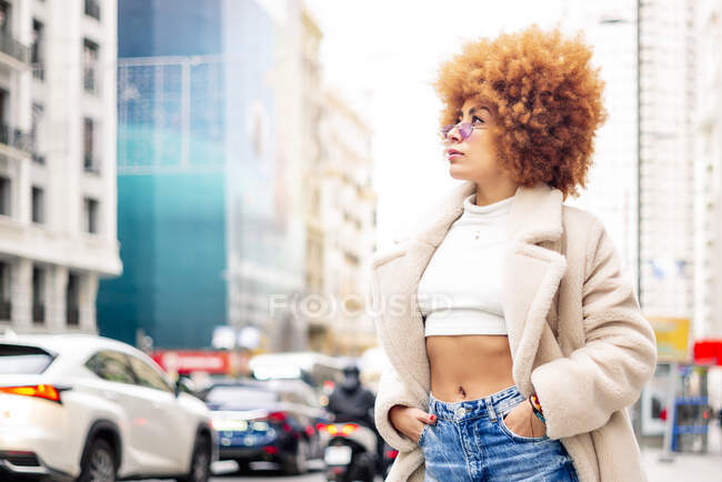 Donna elegante con le mani in tasca contemplando mentre in piedi sulla strada — Foto stock