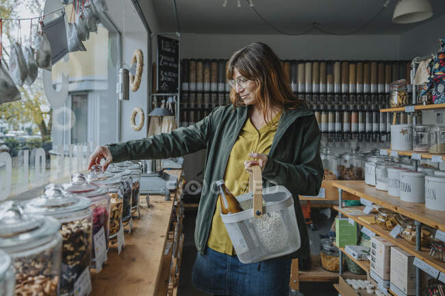 Женщина в очках с корзиной в магазине мусора — стоковое фото