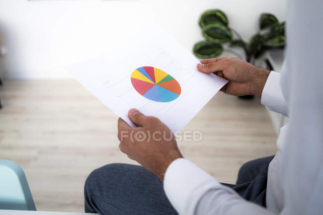 Male entrepreneur holding pie chart while working in office — Stock Photo