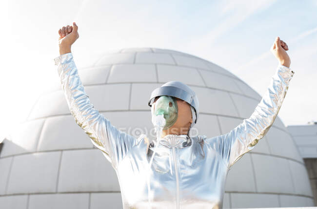 Frau im Schutzanzug mit Sauerstoffmaske und Sonnenbrille jubelt vor Iglu — Stockfoto
