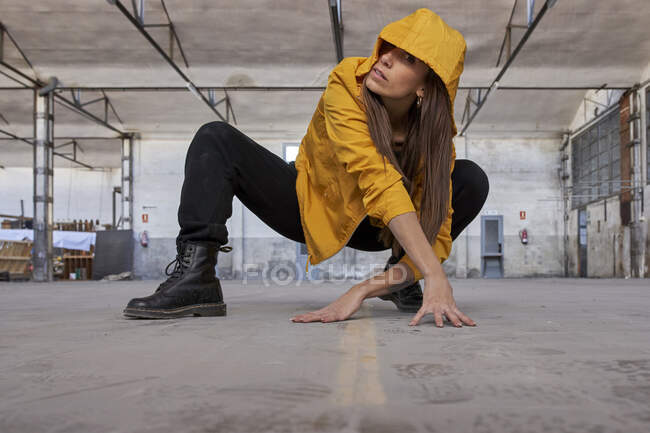 Danseuse moderne en veste jaune pratiquant la danse à l'usine abandonnée — Photo de stock