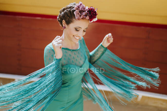 Smiling young woman wearing blue dress and flowers dancing in bullring — Stock Photo
