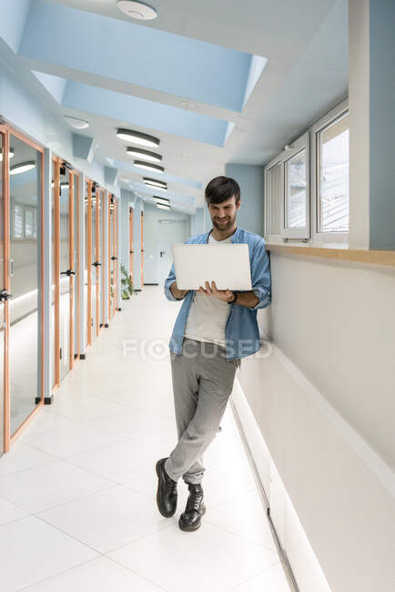 Professionista maschile che lavora sul computer portatile nel corridoio ufficio — Foto stock