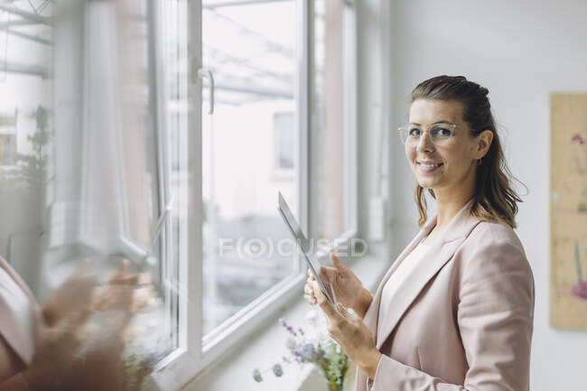 Retrato de mulher de negócios sorridente com tablet digital no escritório — Fotografia de Stock