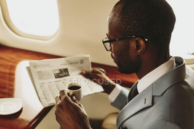 Businessman reading newspaper while traveling in airplane — Stock Photo