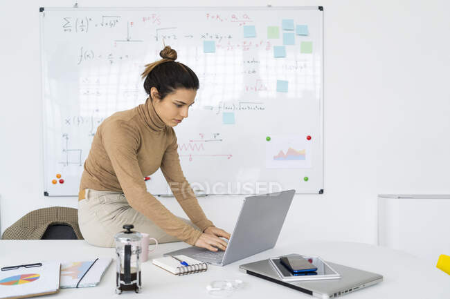 Joven estudiante usando el ordenador portátil mientras hace matemáticas - foto de stock