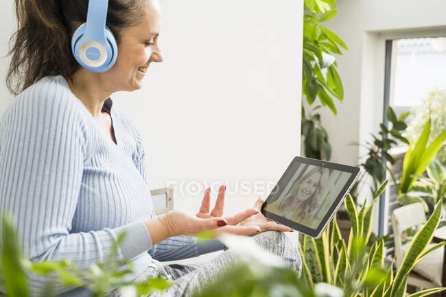 Smiling woman gesturing on video call through digital tablet at home — Stock Photo