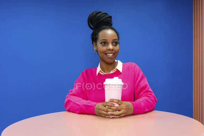 Улыбающаяся женщина-профессионал с многоразовым кофе день чашки мечтает о стене в кафетерии в офисе — стоковое фото