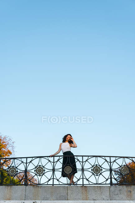 Junge Frau posiert am Wochenende auf Fußgängerbrücke bei klarem Himmel im Park — Stockfoto