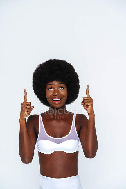 Afro-americano magro mulher vestindo lingerie apontando enquanto em pé contra fundo branco — Fotografia de Stock