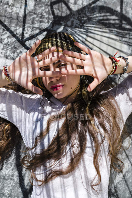 Schöne Frau versteckt Gesicht mit Händen, während sie auf Betonboden liegt — Stockfoto