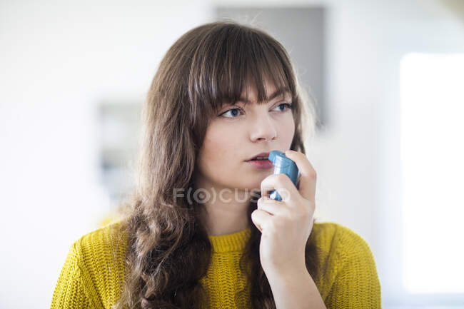 Respiração feminina através do inalador de asma enquanto olha para o lado — Fotografia de Stock