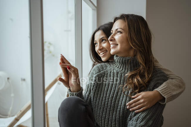 Felice madre e figlia guardando attraverso la finestra mentre seduto a casa — Foto stock