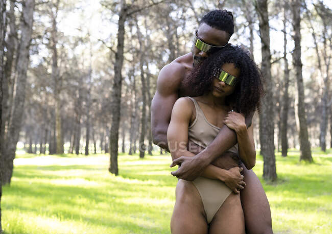 Two professional dancers wearing futuristic goggles embracing in middle of forest — Stock Photo