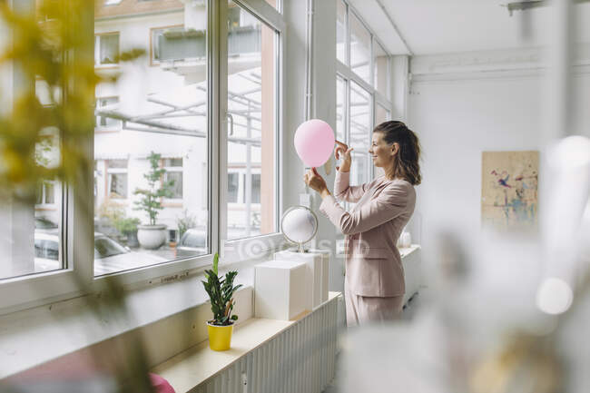 Empresária sorridente segurando balão rosa no escritório — Fotografia de Stock