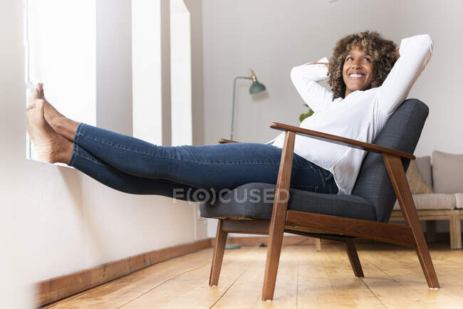 Donna felice sorridente mentre riposa sulla poltrona a casa — Foto stock