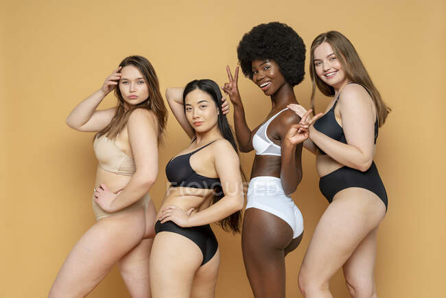 Fiducioso giovani donne in lingerie in piedi contro sfondo giallo — Foto stock