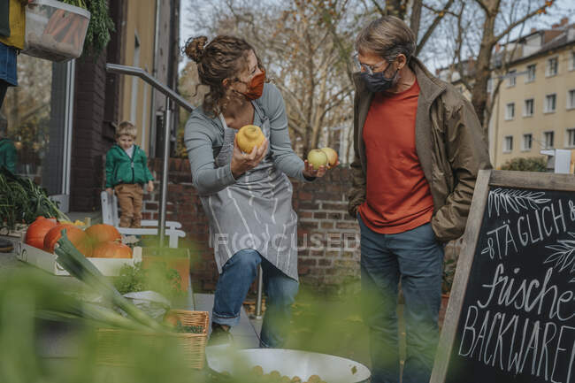 Proprietaria donna che vende mele cotogne a un cliente maschio presso un negozio biologico — Foto stock