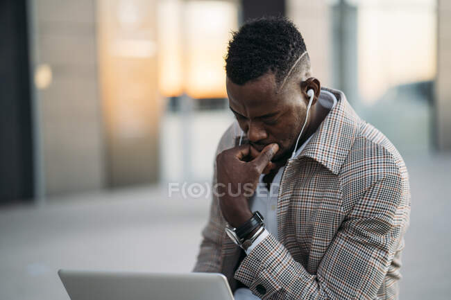 Uomo che utilizza il computer portatile durante l'ascolto di musica — Foto stock