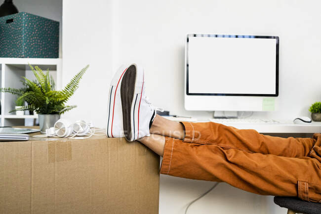 Fatigué jeune femme penché jambes sur la boîte en carton tout en déménageant dans un nouvel appartement — Photo de stock
