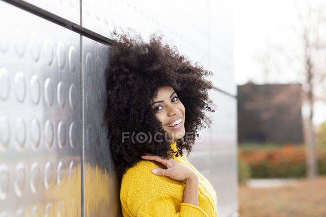 Дивна жінка посміхається, спираючись на срібну стіну — стокове фото