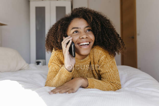 Donna sorridente che parla sul cellulare mentre riposa a casa — Foto stock