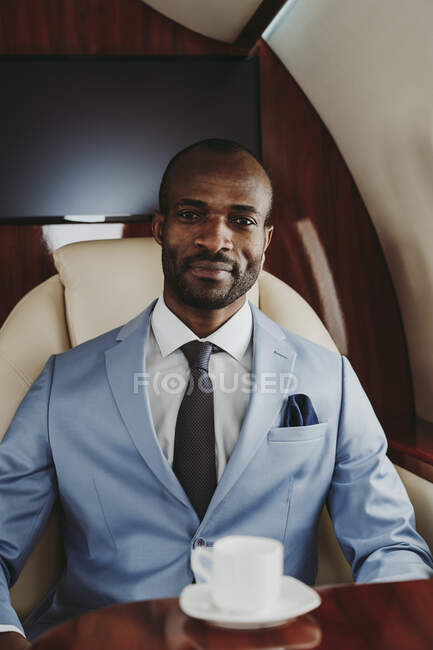 Male entrepreneur with coffee cup in airplane — Stock Photo