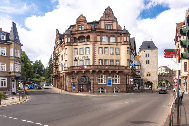 Hotel histórico por estación contra el cielo nublado en la calle Bahnhof y Karl Square en Eisenach, Alemania - foto de stock