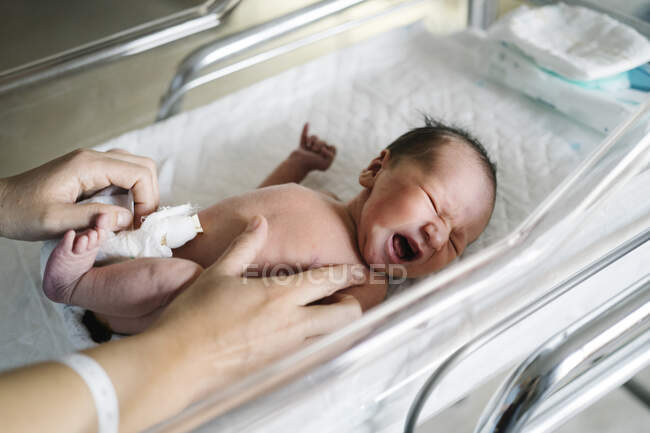 Donna che cambia piangendo bambino bambino pannolino in ospedale — Foto stock