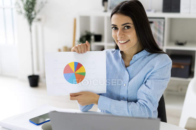 Empresario confiado mostrando gráfico de estrategia de negocio mientras está sentado en la oficina - foto de stock