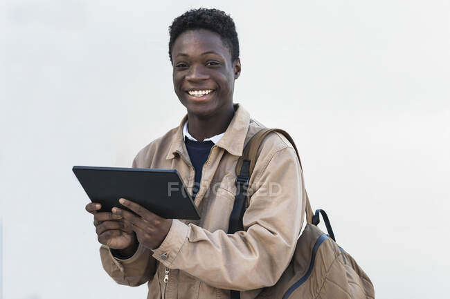 Smiling African man with digital tablet against white wall — Stock Photo