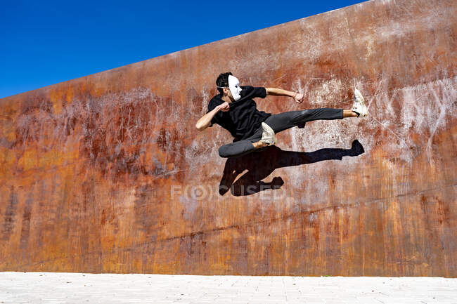 Joven saltando mientras baila contra la pared marrón - foto de stock