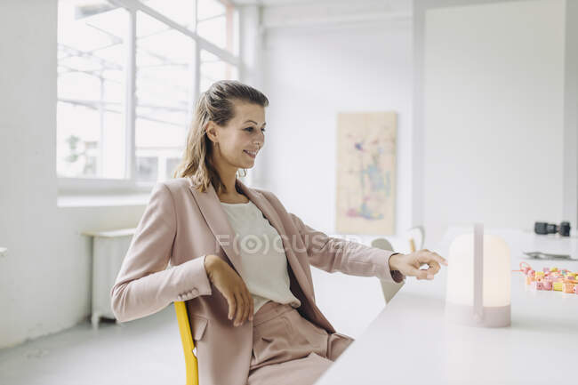 Lächelnde Geschäftsfrau blickt auf Laterne im Büro — Stockfoto