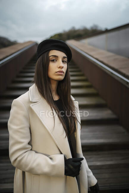 Belle femme portant un manteau debout sur les marches — Photo de stock