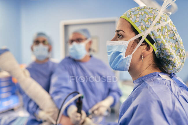Medico donna con maschera protettiva in piedi con collega in sala operatoria in ospedale — Foto stock