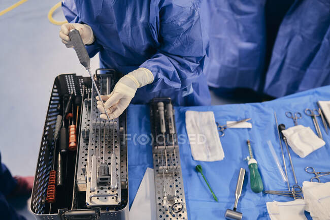 Male doctor choosing medical equipment while standing by table in operating room — Stock Photo