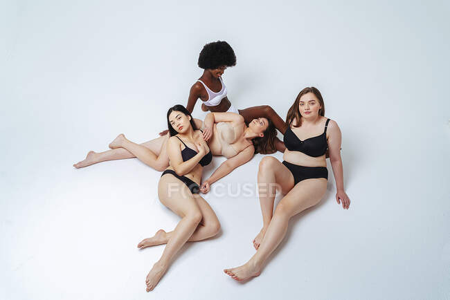 Friends in lingerie resting while lying down at studio — Stock Photo
