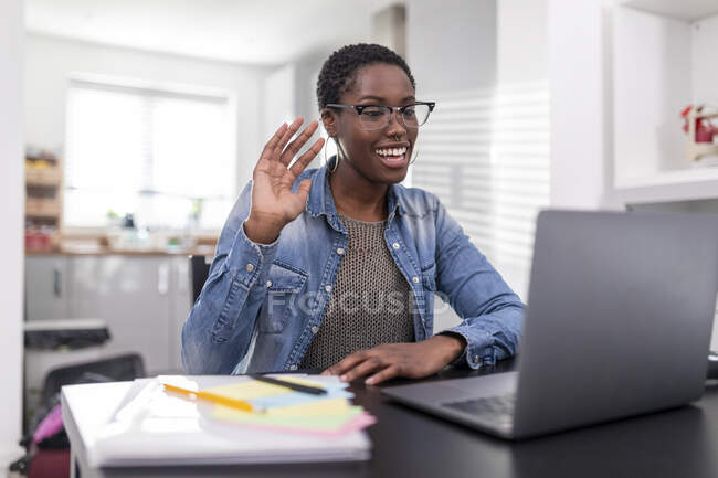 Mujer trabajando teniendo videollamada vía laptop en casa - foto de stock