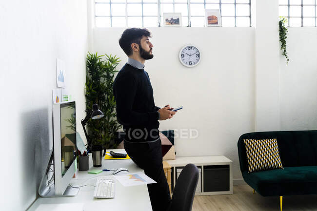Бизнесмен, стоящий за столом в офисе — стоковое фото