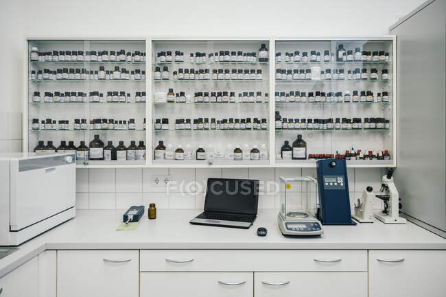 Laptop by device and containers arranged in chemist shop — Stock Photo